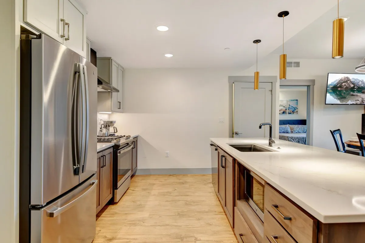 A beautifully appointed kitchen featuring stainless steel appliances, a spacious island with an integrated sink, striking pendant lighting, and warm wooden cabinetry. The scene feels both functional and inviting, designed for both serious cooking and social gatherings.