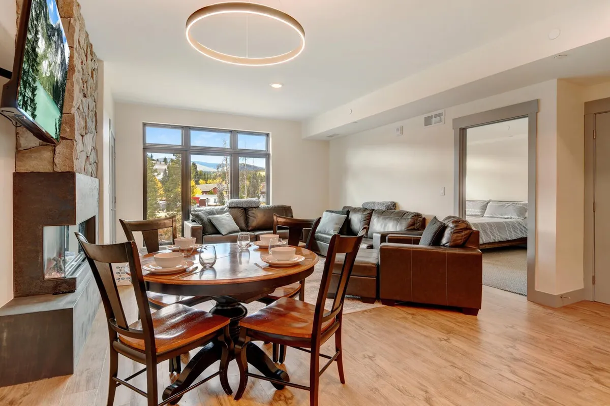 A sophisticated dining area with a table set for a meal, comfortable seating, and an adjacent cozy sitting space with a fireplace. The mood is inviting and warm, perfect for family dinners or lingering over shared meals.